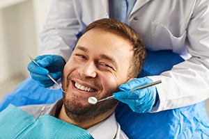 A smiling, bearded man receiving a dental checkup