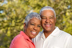 couple with dental implants in Shorewood standing among trees