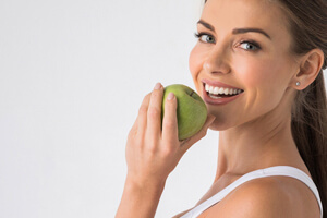 young woman biting into a green apple