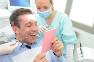 dental patient admiring his new smile in a mirror