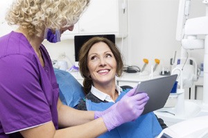 Dentist smiling at patient while taking notes on clipboard