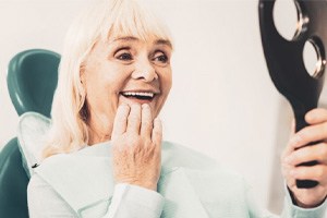 Woman smiling while holding handheld mirror at checkup