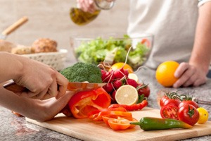 Closeup of patient preparing vegetables on a cutting board at home