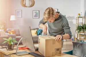 Man using scissors to open package at his desk