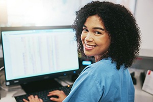 Smiling dental team member sitting at computer