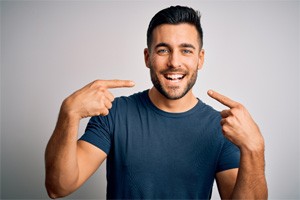 Smiling man pointing to his white teeth
