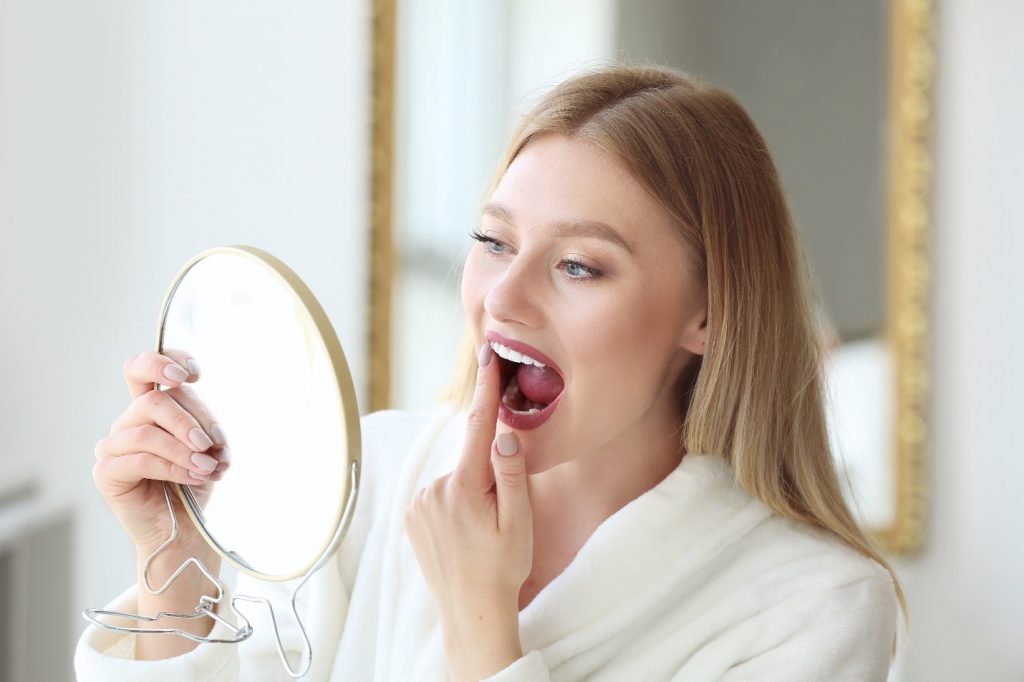 Woman looking at teeth and gums in the mirror